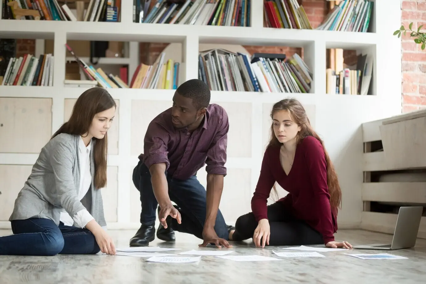 オフィスの床で協力してブレインストーミングしている若いプロジェクトチーム、チームワーク。